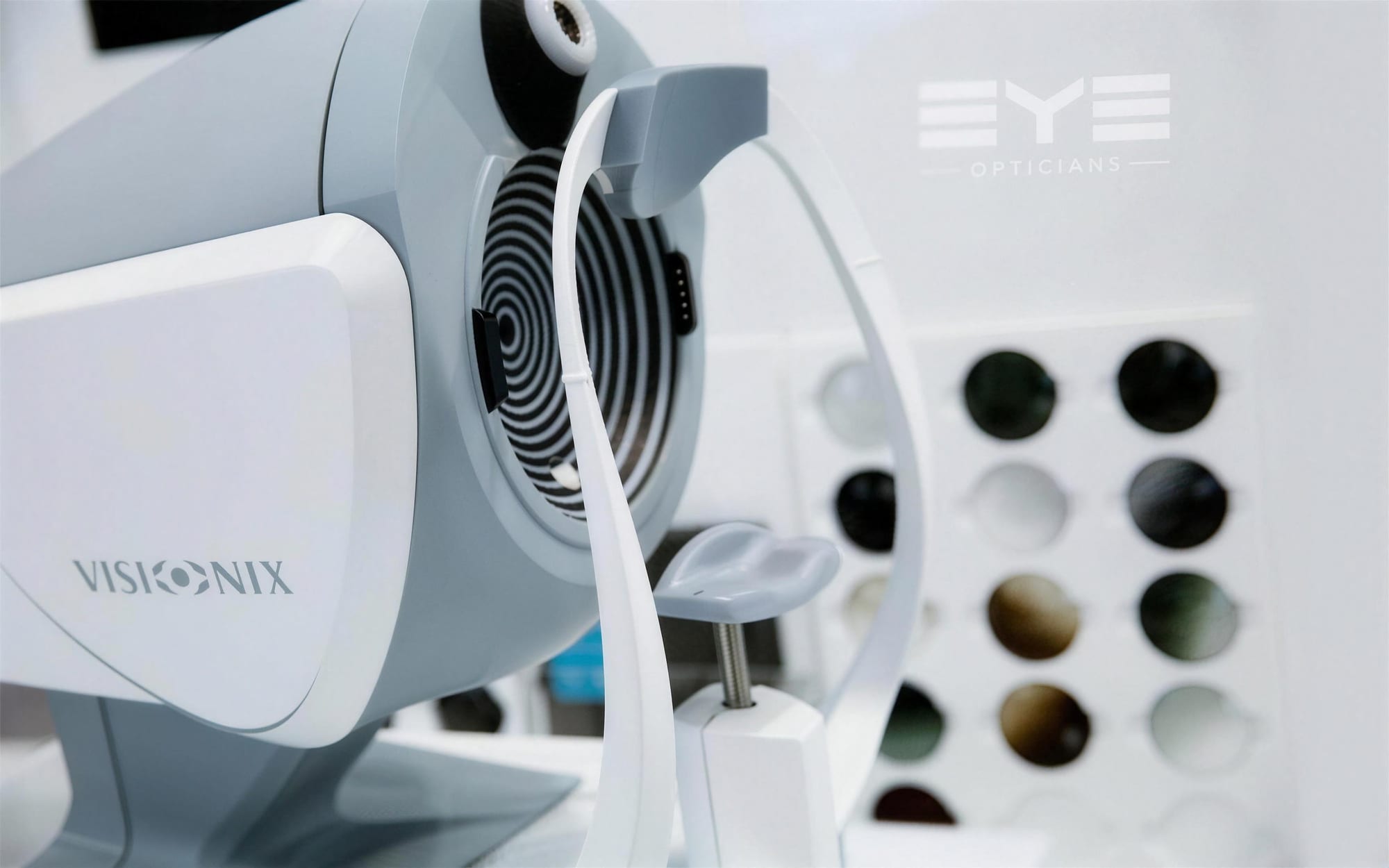 A Visionix diagnostic instrument in front of a display of sunglass lenses at EYE Opticians, Edgbaston
