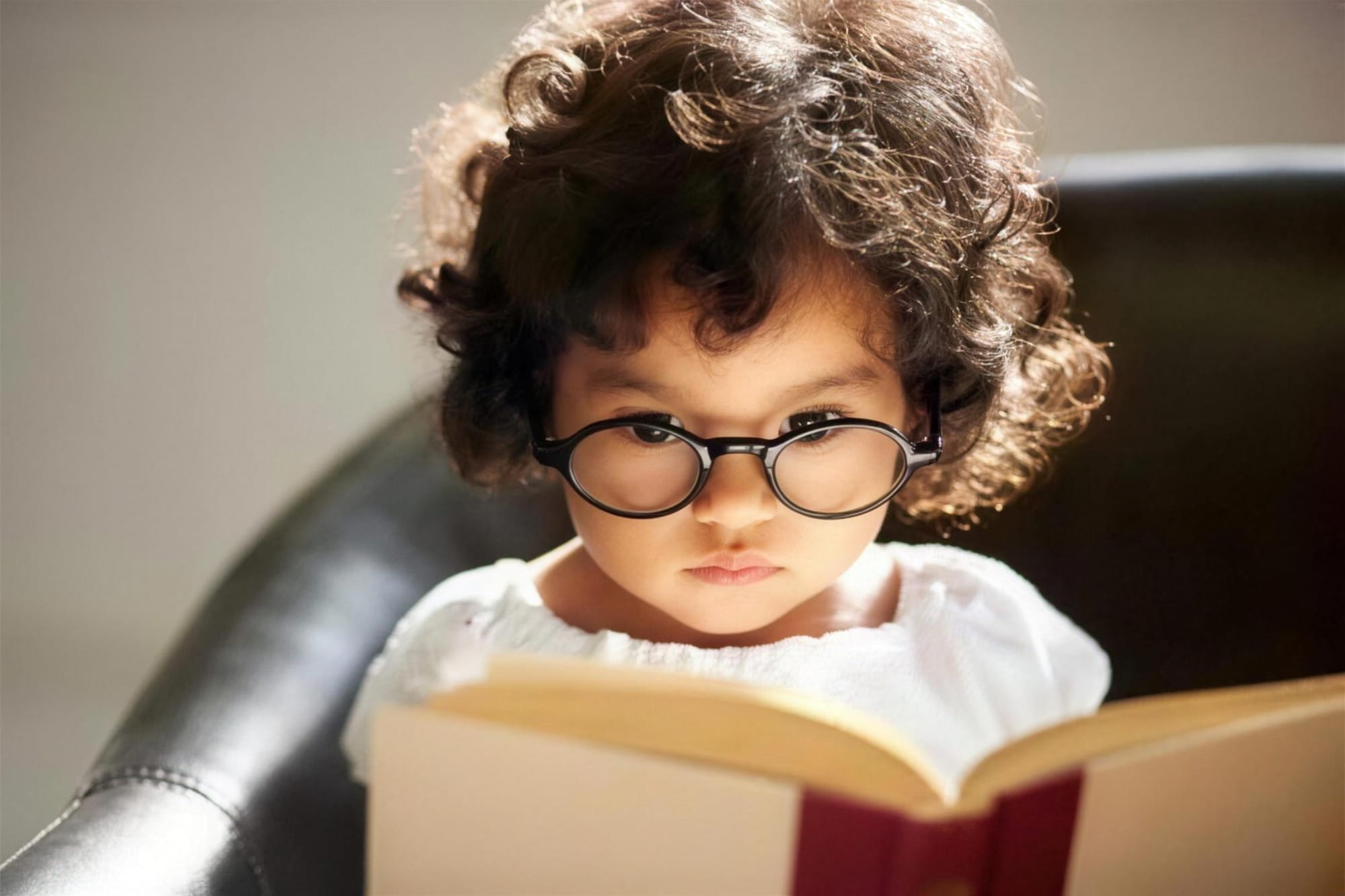 A young child in glasses reading a book