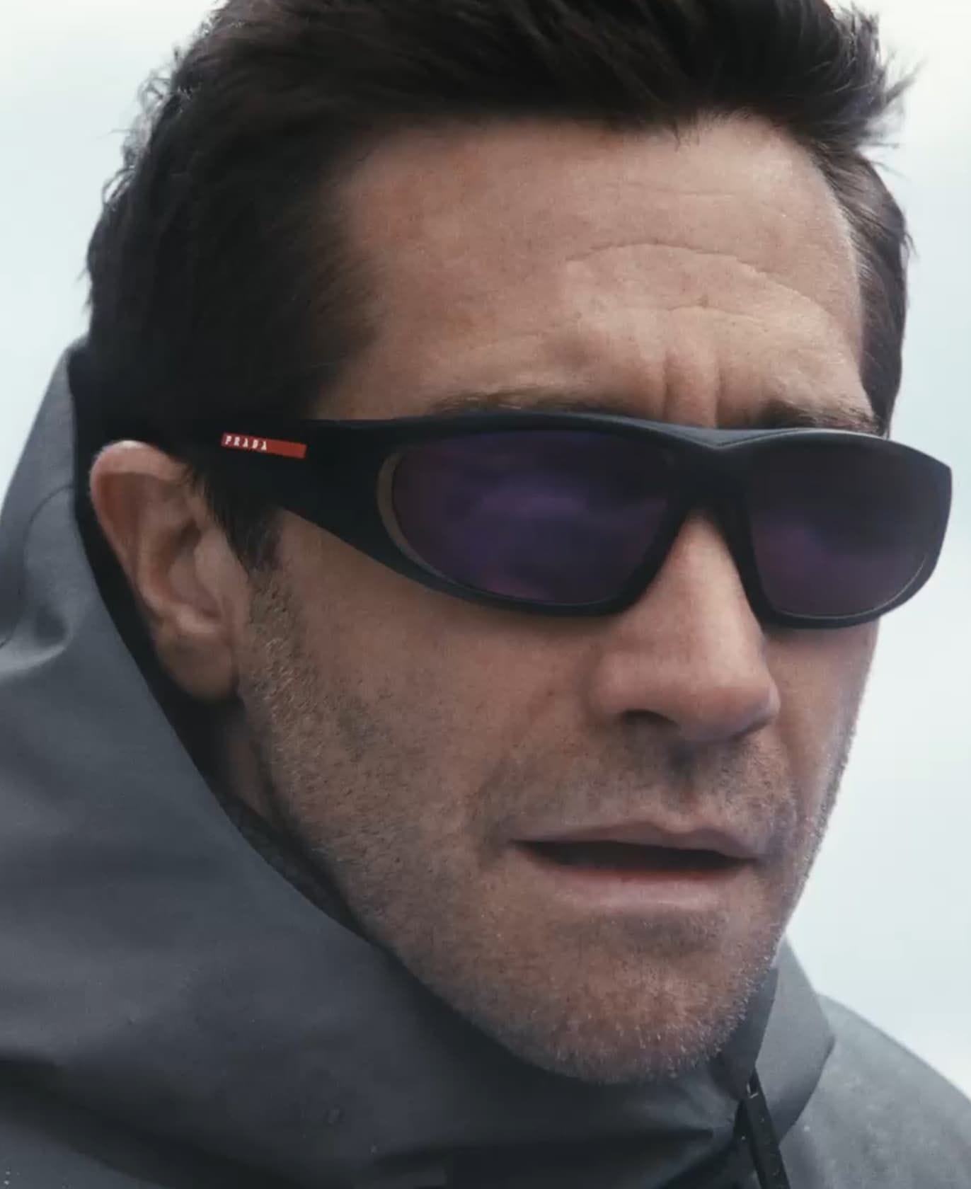 A man in a grey hood wearing Prada Linea Rossa sunglasses
