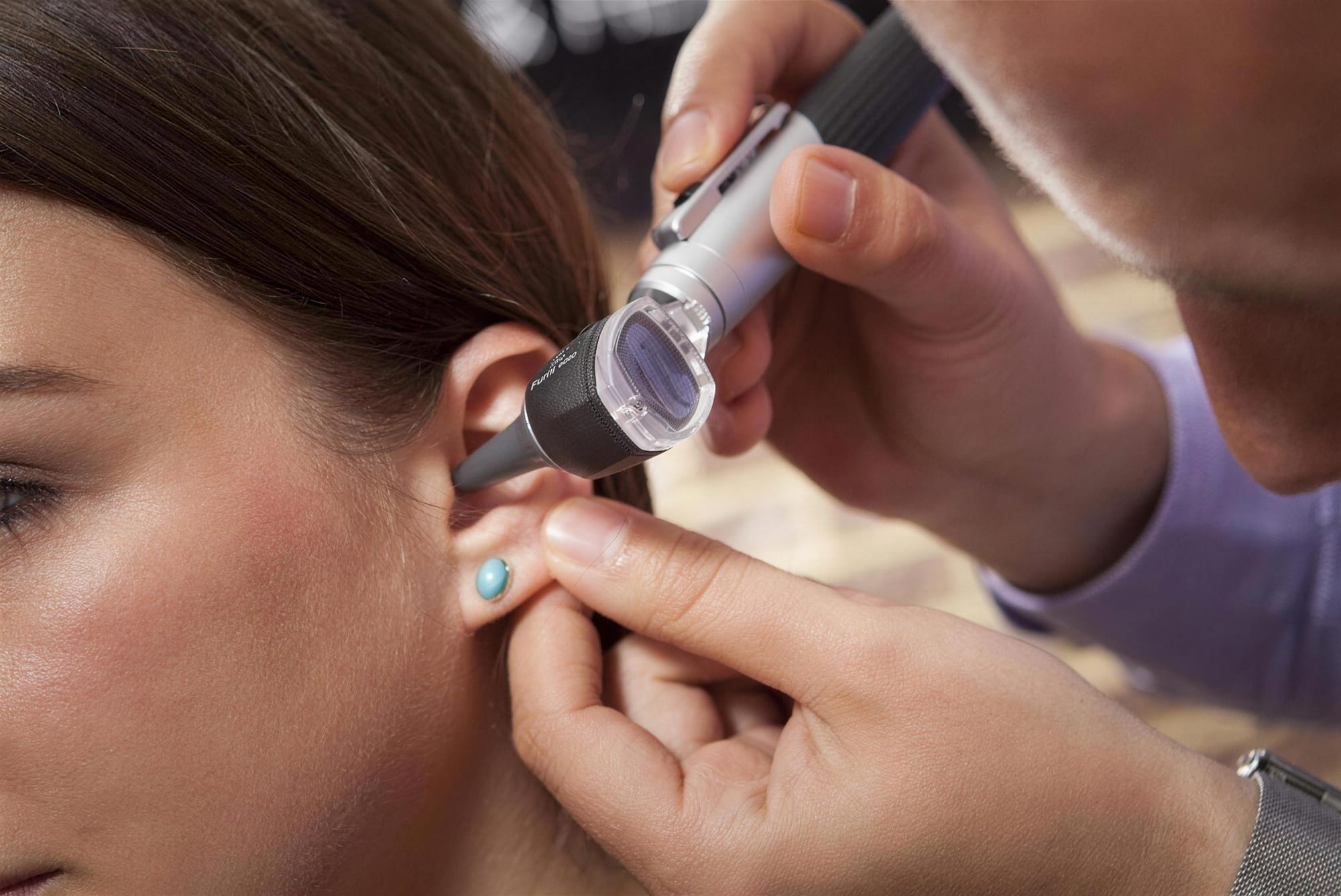 An audiologist examining a patient's ear