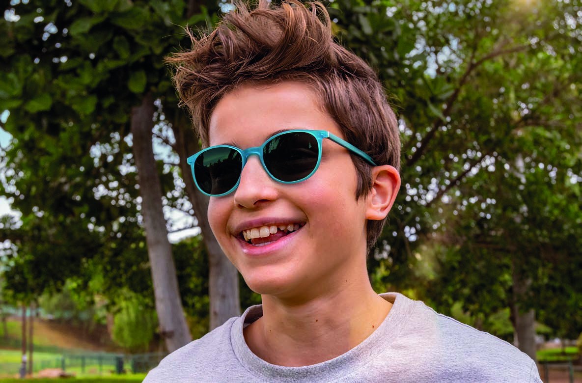A boy outdoors in glasses with MiYOSMART Chameleon lenses darkened by the sun