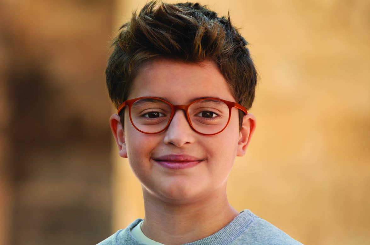 A smiling boy wearing red glasses with MiYOSMART lenses