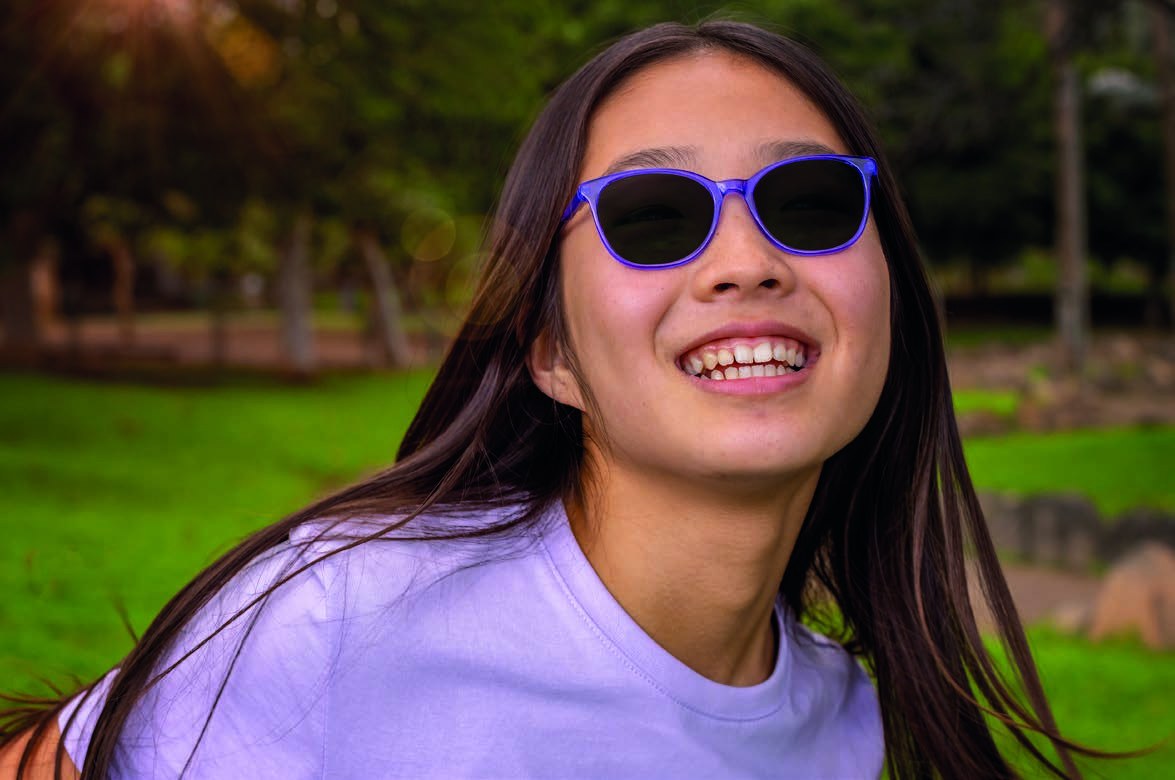 A girl smiling in a park wearing MiYOSMART Sunbird polarised sun lenses