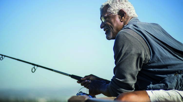 A man in glasses fishing on a bright day
