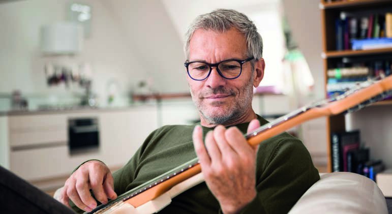 A man in glasses playing guitar at home