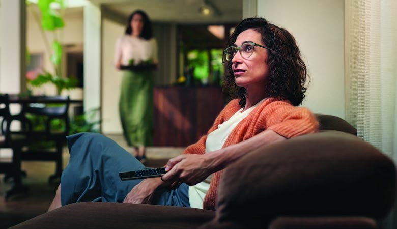 A woman in glasses relaxing on a sofa at home