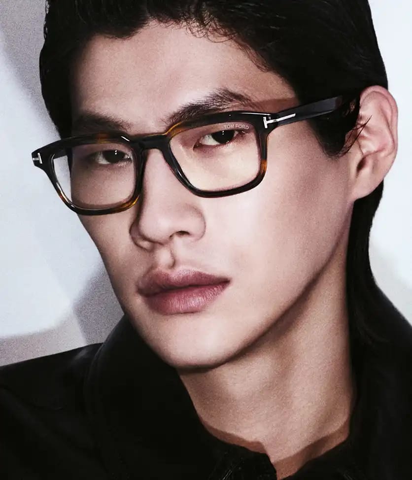 A man wearing dark tortoiseshell Tom Ford optical frames
